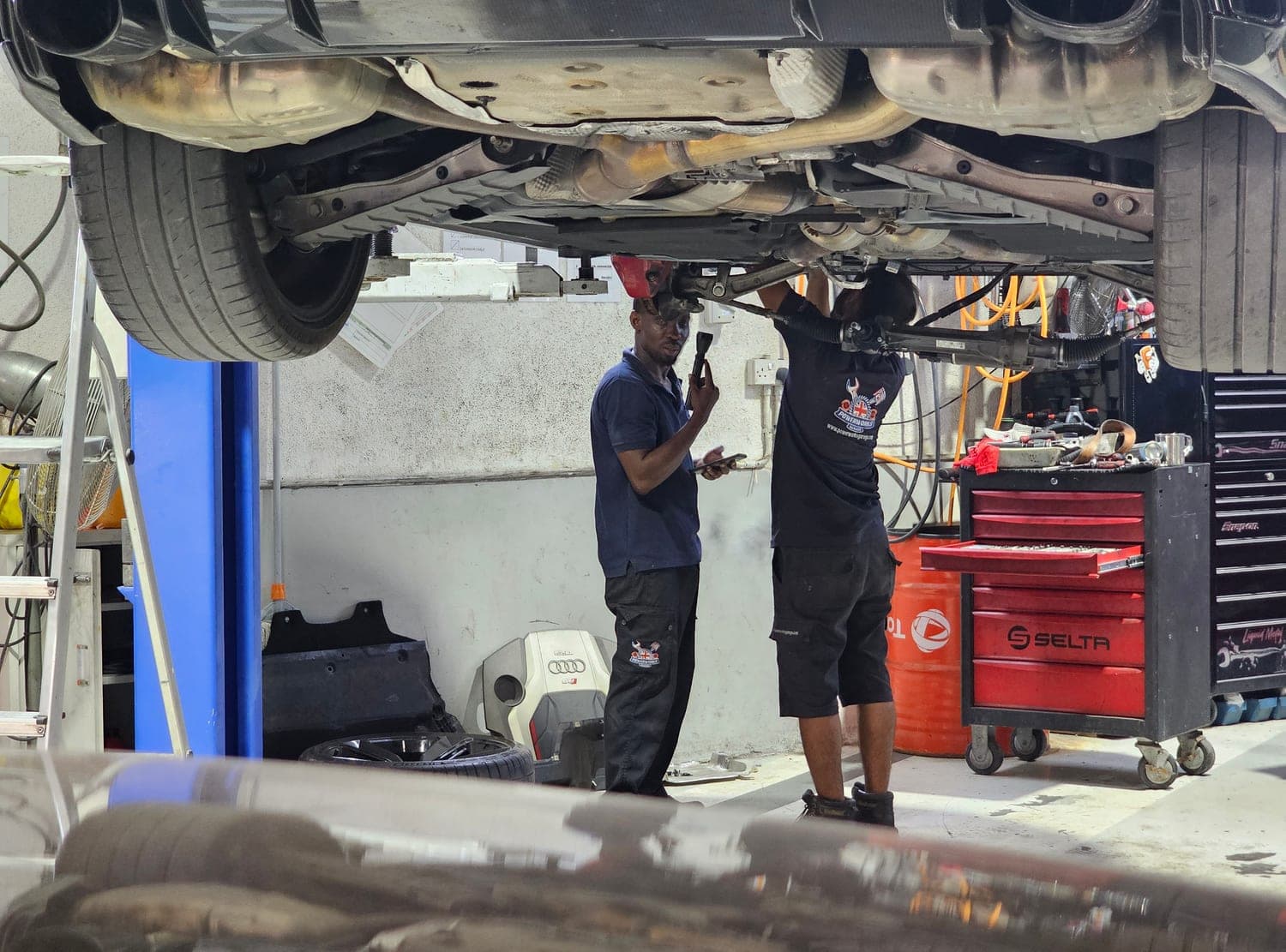 Underside of a customer car raised on a two-post lift at Powerworks