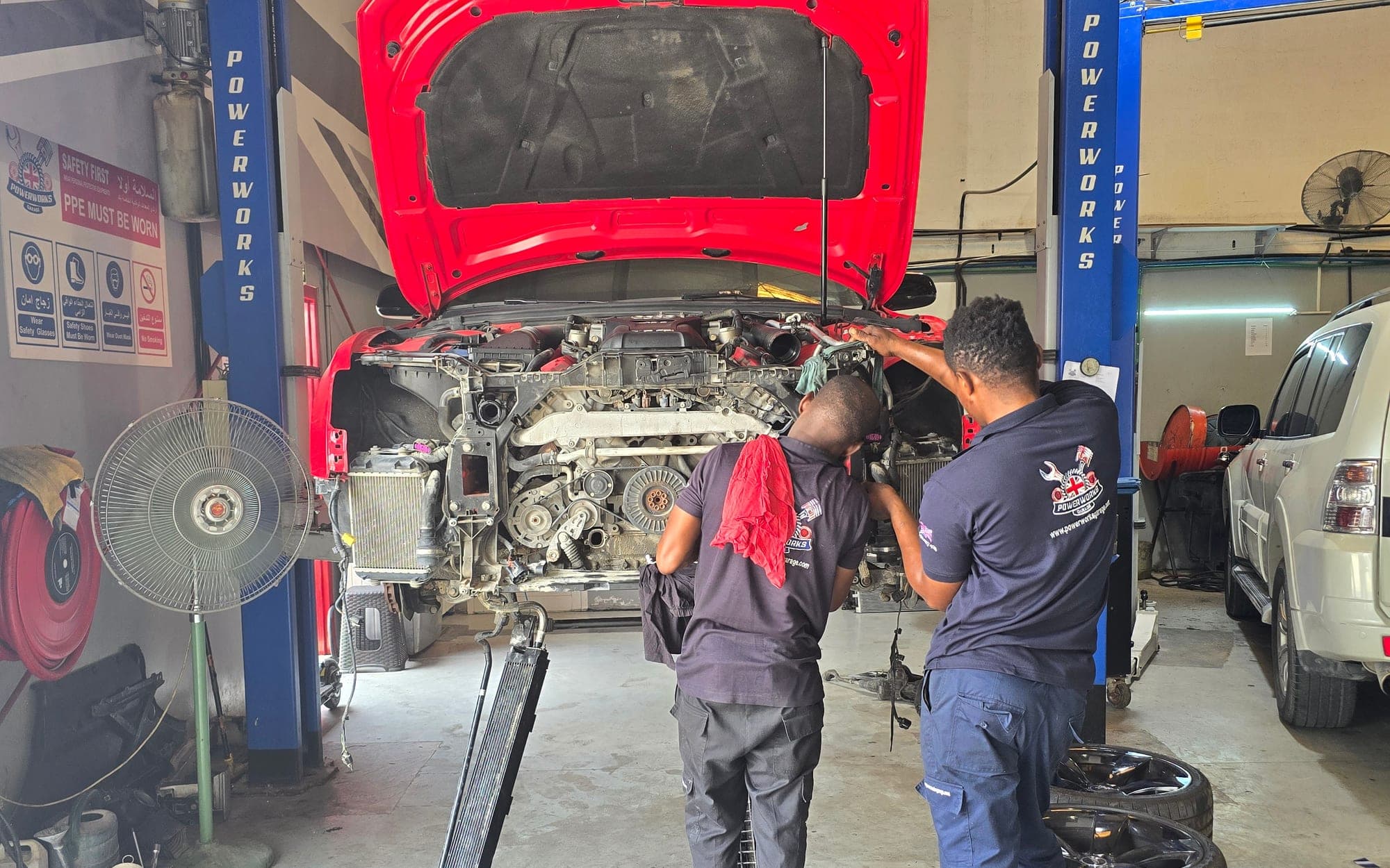 Powerworks technicians working on a car raised on a two-post lift in the Dubai workshop
